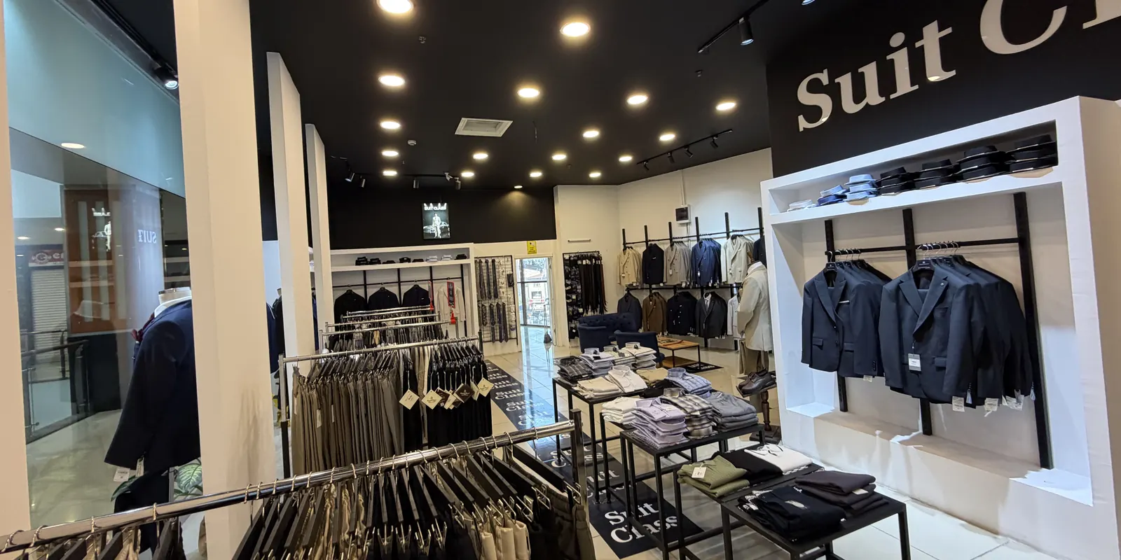 Mağazada askıda pantolon, ceket ve katlanmış gömlekler